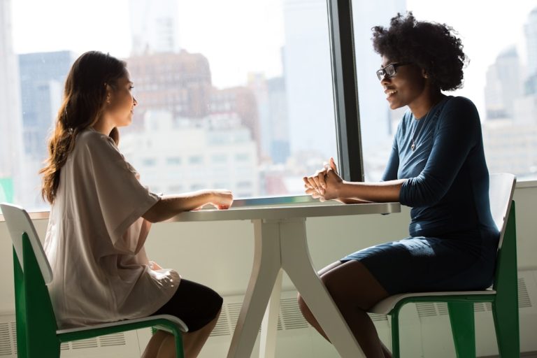 two-women-sitting-beside-table-and-talking-lq1t-8ms5py